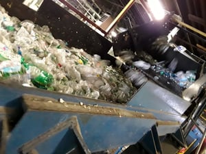 PET bottles on conveyer belt at PQ Recycling plant; soon they will converted to flake for reuse to make new bottles, packaging, and other PET products like strapping tape.